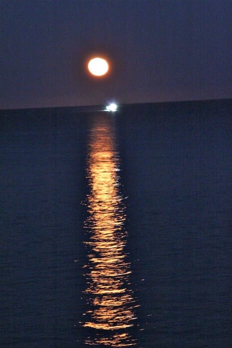 fishing boat crossing moon's path